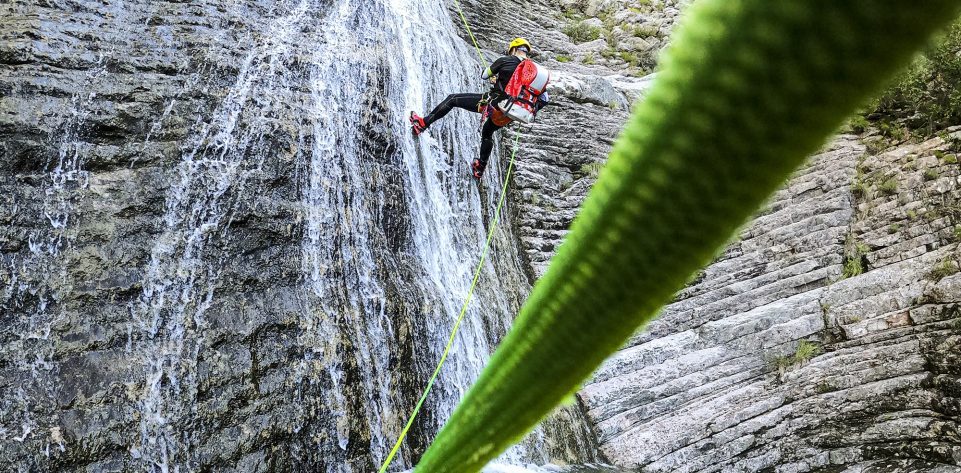 Canyoneering male adventurer seen from below rappelling down the waterfall in an amazing canyon in Montenegro.
